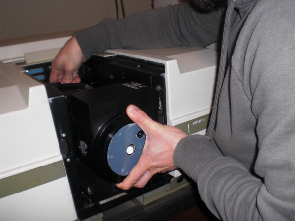 two hands placing a cell in a Cary 5 E UV-Vis-NIR spectrometer